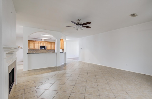 12223 Ayrshire Pl, Houston, TX 77089 - unfurnished living room with ceiling fan, light tile patterned floors, a fireplace, and arched walkways
