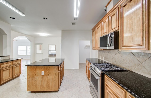 12223 Ayrshire Pl, Houston, TX 77089 - kitchen featuring stainless steel appliances, arched walkways, backsplash, a center island, and light tile patterned flooring