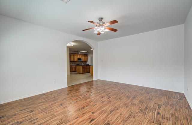 12223 Ayrshire Pl, Houston, TX 77089 - unfurnished room featuring ceiling fan, arched walkways, light wood-type flooring, and baseboards