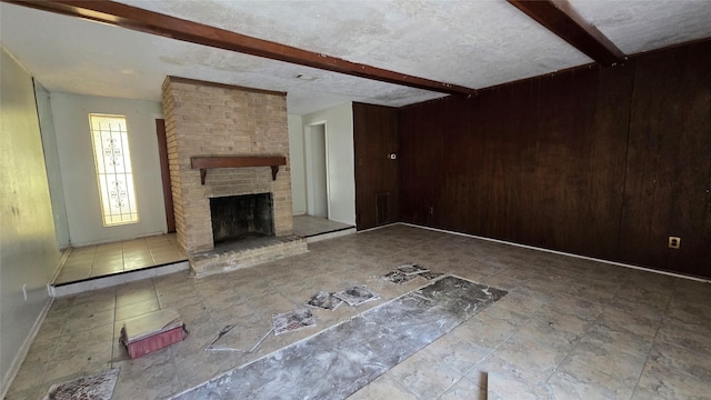 3823 Regency Dr, Houston, TX 77045 - unfurnished living room with beamed ceiling, stone finish floors, wooden walls, a fireplace, and baseboards