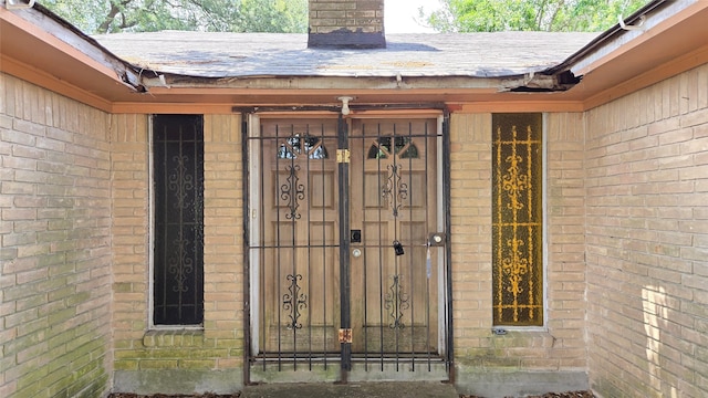 3823 Regency Dr, Houston, TX 77045 - view of exterior entry featuring brick siding, roof with shingles, and a chimney