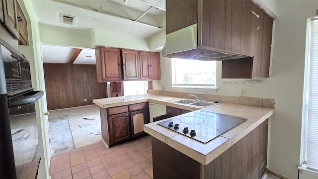 3823 Regency Dr, Houston, TX 77045 - kitchen with a peninsula, a sink, electric cooktop, tile counters, and under cabinet range hood