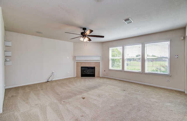17919 Royal Gate Ln, Richmond, TX 77407 - unfurnished living room featuring carpet flooring, ceiling fan, a tiled fireplace, baseboards, and a textured ceiling
