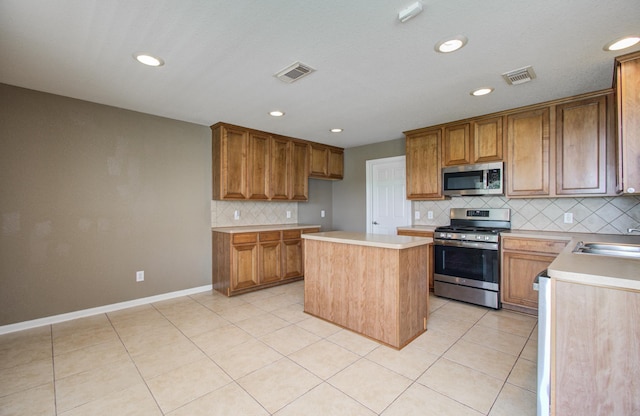 17919 Royal Gate Ln, Richmond, TX 77407 - kitchen featuring appliances with stainless steel finishes, decorative backsplash, light countertops, light tile patterned flooring, and a kitchen island