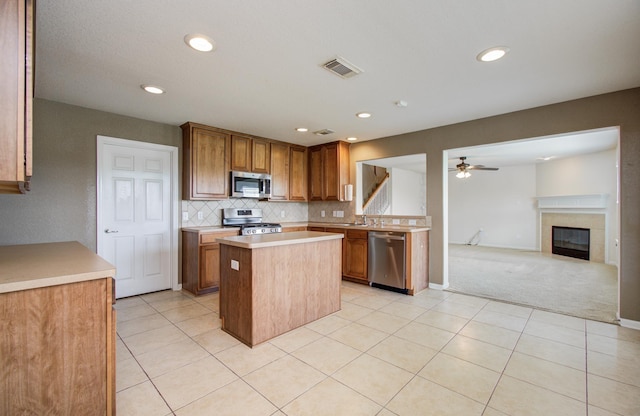 17919 Royal Gate Ln, Richmond, TX 77407 - kitchen with stainless steel appliances, a ceiling fan, light countertops, a center island, and tasteful backsplash