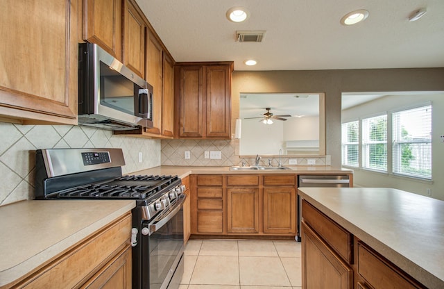 17919 Royal Gate Ln, Richmond, TX 77407 - kitchen featuring stainless steel appliances, a sink, brown cabinetry, ceiling fan, and recessed lighting