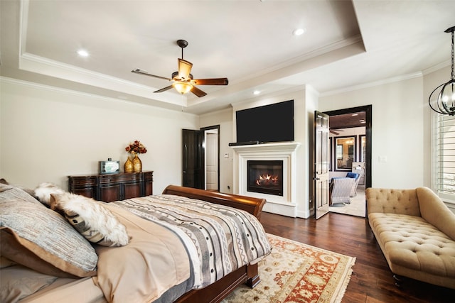9 Copper Bottom Dr, Tomball, TX 77377 - bedroom featuring a raised ceiling, a glass covered fireplace, crown molding, dark wood finished floors, and recessed lighting