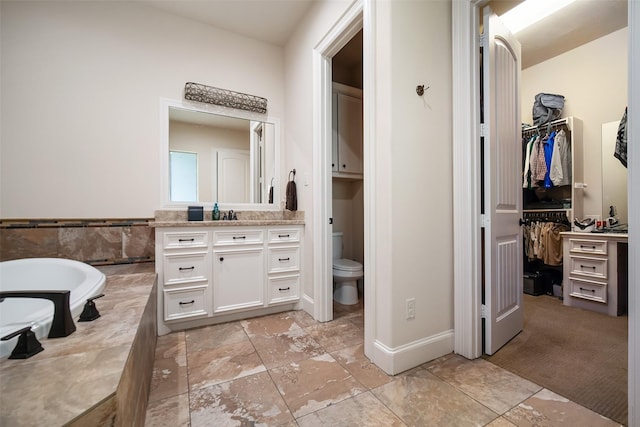 9 Copper Bottom Dr, Tomball, TX 77377 - bathroom with vanity, a walk in closet, a tub to relax in, and toilet