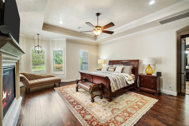 9 Copper Bottom Dr, Tomball, TX 77377 - bedroom featuring a raised ceiling, a glass covered fireplace, dark wood-type flooring, baseboards, and ornamental molding
