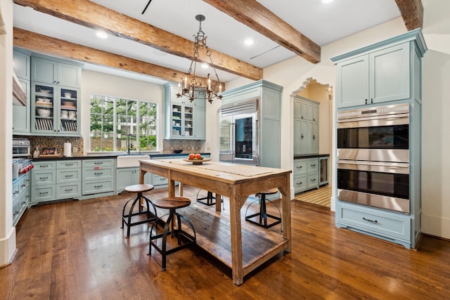 1915 Kirby Dr, Houston, TX 77019 - kitchen featuring stainless steel appliances, dark wood-style floors, decorative backsplash, a sink, and a chandelier