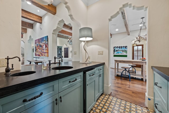 1915 Kirby Dr, Houston, TX 77019 - kitchen featuring a sink, beamed ceiling, dark countertops, a chandelier, and decorative light fixtures