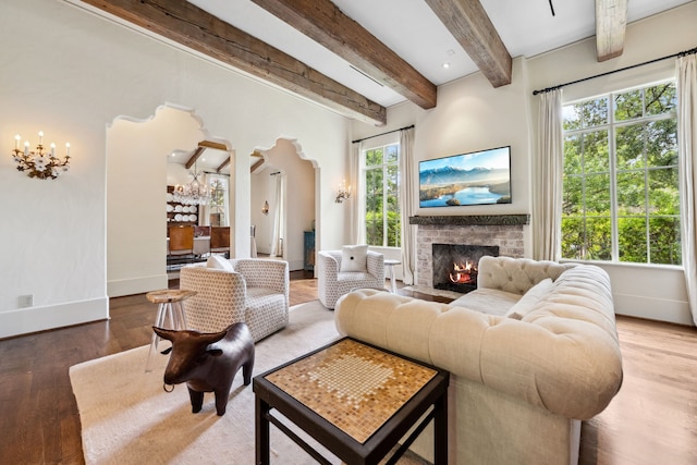 1915 Kirby Dr, Houston, TX 77019 - living area featuring arched walkways, healthy amount of natural light, wood finished floors, a warm lit fireplace, and beam ceiling