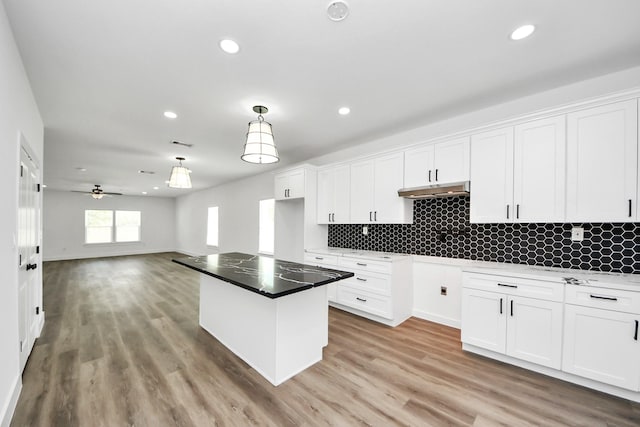 5046 Muske Ln, Brookshire, TX 77423 - kitchen with white cabinetry, recessed lighting, under cabinet range hood, backsplash, and light wood-style flooring