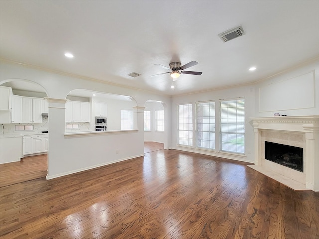 2927 Cambry Crossing Ct, Katy, TX 77494 - unfurnished living room featuring a ceiling fan, crown molding, a fireplace, wood finished floors, and ornate columns