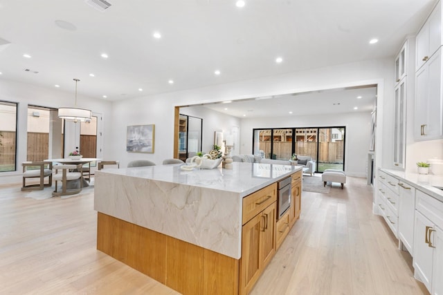 1526 Wakefield Dr, Houston, TX 77018 - kitchen featuring stainless steel microwave, light wood-style floors, a large island, light stone countertops, and recessed lighting