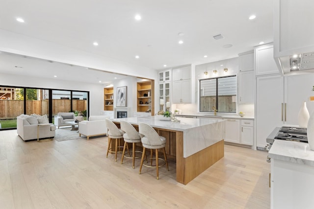 1526 Wakefield Dr, Houston, TX 77018 - kitchen with light wood finished floors, white cabinetry, a center island, recessed lighting, and a kitchen bar