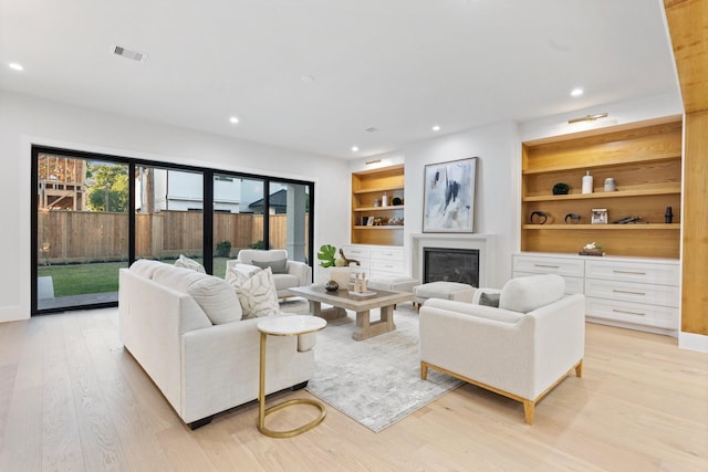 1526 Wakefield Dr, Houston, TX 77018 - living area with light wood finished floors, recessed lighting, a glass covered fireplace, built in shelves, and baseboards
