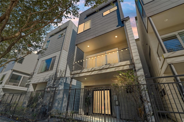 2809 St Emanuel St, Houston, TX 77004 - back of property at dusk with a balcony, a fenced front yard, and a gate