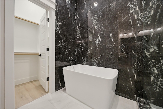4825 Pederson St A/B, Unit A/B Houston, TX 77033 - bathroom featuring a spacious closet, a soaking tub, marble tiled flooring, and tile walls