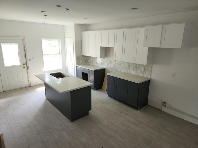 8208/8210 Knox St, Houston, TX 77088 - kitchen with decorative backsplash, a center island with sink, white cabinetry, and light wood-type flooring
