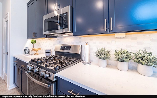12018 Wooden Mill Ln, Santa Fe, TX 77510 - kitchen with appliances with stainless steel finishes, blue cabinets, light countertops, backsplash, and light wood finished floors