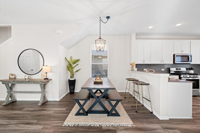 17810 Planted Orchard Dr, Hockley, TX 77447 - kitchen with appliances with stainless steel finishes, dark wood finished floors, a breakfast bar area, white cabinetry, and a chandelier