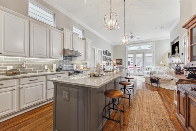 414 E 28th St, Houston, TX 77008 - kitchen with dark wood-type flooring, open floor plan, a chandelier, ornamental molding, and white cabinets