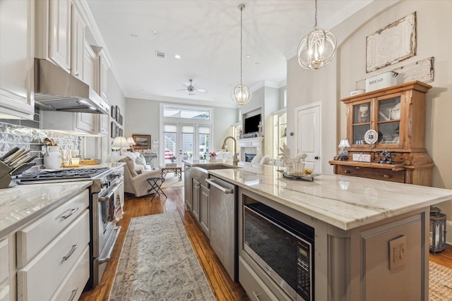 414 E 28th St, Houston, TX 77008 - kitchen with stainless steel appliances, open floor plan, under cabinet range hood, ornamental molding, and dark wood-type flooring