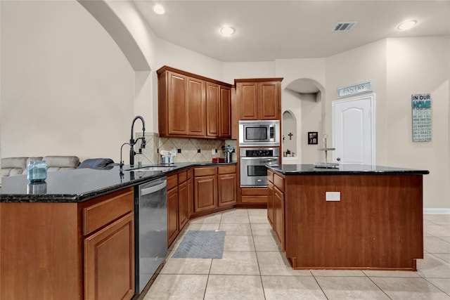 22734 Newcourt Place St, Tomball, TX 77375 - kitchen featuring appliances with stainless steel finishes, a sink, a kitchen island, arched walkways, and decorative backsplash