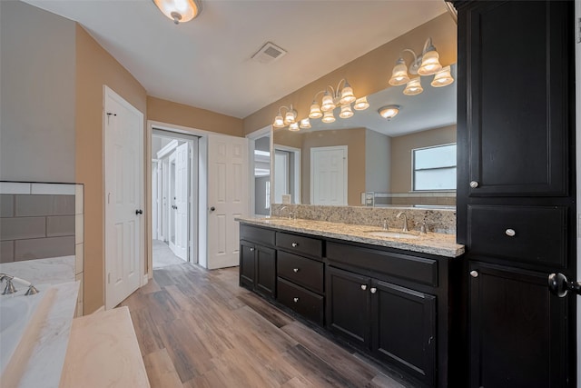 15509 Lakeview Dr, Jersey Village, TX 77040 - bathroom featuring double vanity, a bath, a chandelier, and wood finished floors