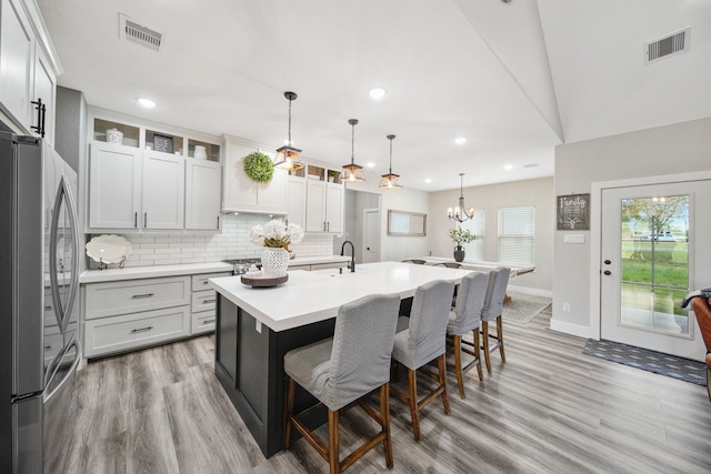 7332 Kurt Dr, Brenham, TX 77833 - kitchen with freestanding refrigerator, a kitchen bar, light wood finished floors, an island with sink, and light countertops