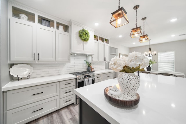 7332 Kurt Dr, Brenham, TX 77833 - kitchen featuring light countertops, decorative backsplash, hanging light fixtures, wood finished floors, and glass insert cabinets
