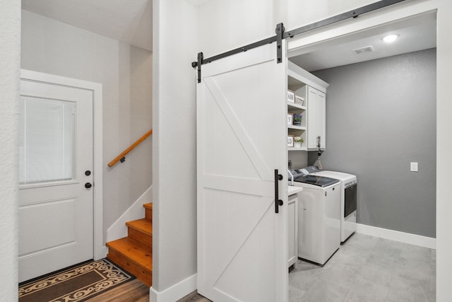 7332 Kurt Dr, Brenham, TX 77833 - laundry area with a barn door, cabinet space, washing machine and clothes dryer, and baseboards