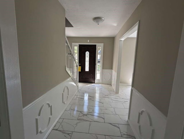 706 Redleaf Ln, Houston, TX 77090 - foyer with light marble finish flooring, a wainscoted wall, stairs, and a textured ceiling