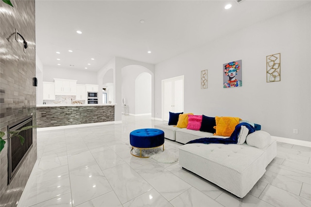 19236 Yellow Chestnut Ln, New Caney, TX 77357 - living room featuring light marble finish floors, arched walkways, a fireplace, recessed lighting, and baseboards