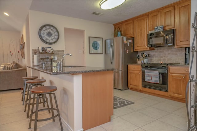 22113 Matagorda Dr, Galveston, TX 77554 - kitchen featuring black appliances, a sink, decorative backsplash, a breakfast bar, and dark stone countertops