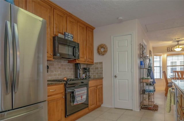 22113 Matagorda Dr, Galveston, TX 77554 - kitchen featuring black appliances, light tile patterned flooring, tasteful backsplash, brown cabinetry, and a textured ceiling