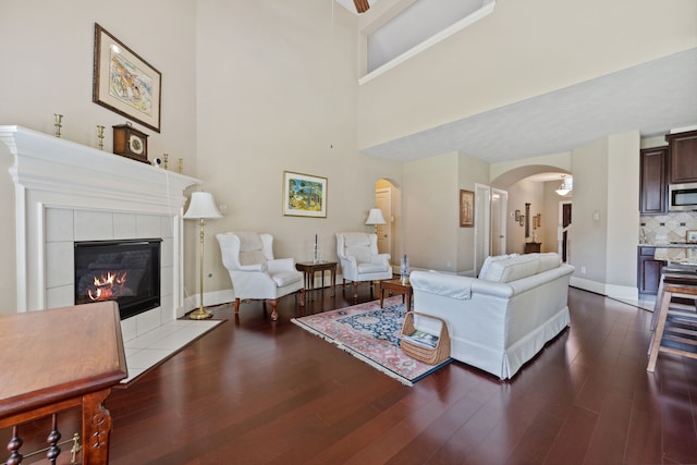 14418 Brushy Arbor Ln, Humble, TX 77396 - living room with arched walkways, wood finished floors, a fireplace, a towering ceiling, and baseboards