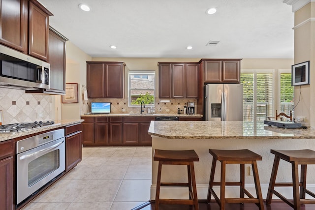 14418 Brushy Arbor Ln, Humble, TX 77396 - kitchen with appliances with stainless steel finishes, a breakfast bar, tasteful backsplash, light stone countertops, and recessed lighting