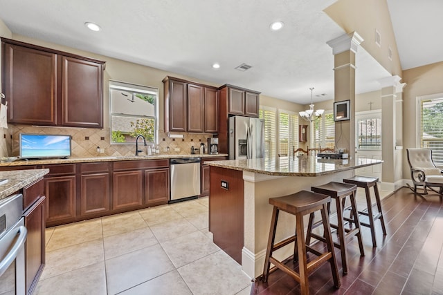 14418 Brushy Arbor Ln, Humble, TX 77396 - kitchen with appliances with stainless steel finishes, a chandelier, a kitchen bar, light stone countertops, and recessed lighting