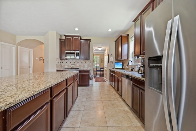 14418 Brushy Arbor Ln, Humble, TX 77396 - kitchen with appliances with stainless steel finishes, decorative backsplash, light stone counters, light tile patterned flooring, and a sink