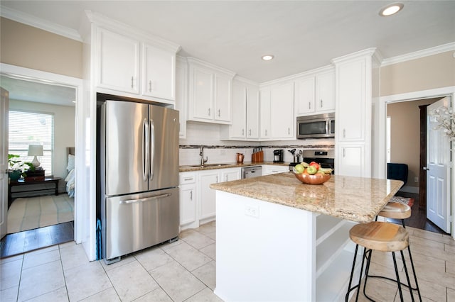 2116 Carter St, Houston, TX 77008 - kitchen featuring stainless steel appliances, a sink, a kitchen island, tasteful backsplash, and white cabinets