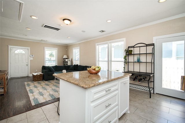 2116 Carter St, Houston, TX 77008 - kitchen with a center island, recessed lighting, white cabinetry, light tile patterned floors, and light stone counters