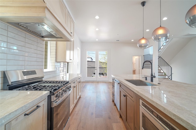 5439 Darling St, Houston, TX 77007 - kitchen featuring stainless steel appliances, a sink, light stone countertops, light wood finished floors, and decorative backsplash