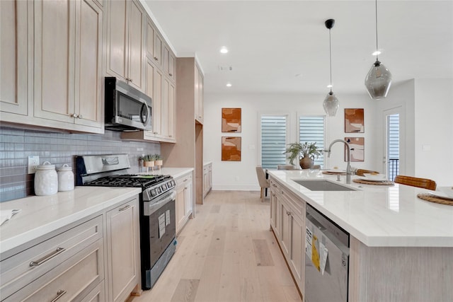 5439 Darling St, Houston, TX 77007 - kitchen with stainless steel appliances, a sink, decorative backsplash, light wood-style flooring, and an island with sink
