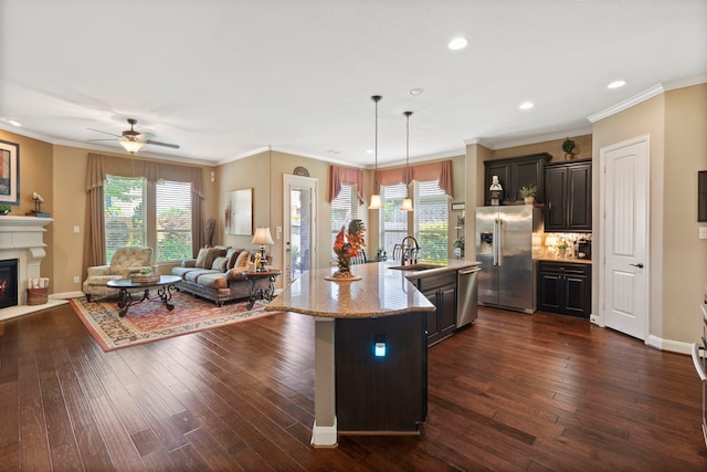 24119 Blue Crest Dr, Porter, TX 77365 - kitchen featuring stainless steel appliances, a sink, open floor plan, a glass covered fireplace, and dark wood-style flooring