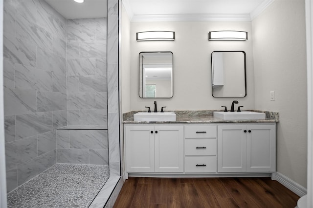809 E Bowie Ave, Crockett, TX 75835 - bathroom featuring crown molding, wood finished floors, double vanity, a tile shower, and baseboards