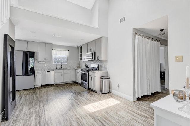 19011 Sandia Pines Dr, Humble, TX 77346 - kitchen featuring appliances with stainless steel finishes, a sink, light wood-style flooring, light countertops, and tasteful backsplash