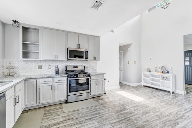 19011 Sandia Pines Dr, Humble, TX 77346 - kitchen featuring stainless steel appliances, decorative backsplash, light wood-style floors, light stone countertops, and baseboards