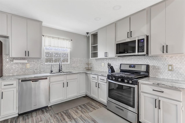 19011 Sandia Pines Dr, Humble, TX 77346 - kitchen with appliances with stainless steel finishes, a sink, open shelves, wood finished floors, and decorative backsplash